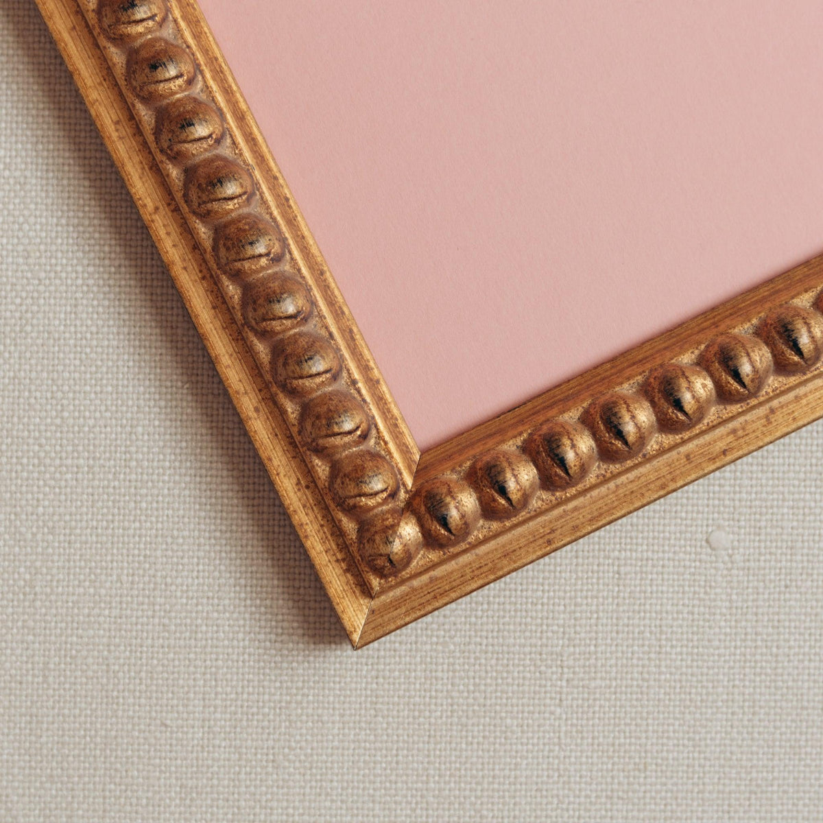 Detailed corner shot of handmade bobbin antique style gold frame with pink mount on a linen background. Only available at Giddy Prints.