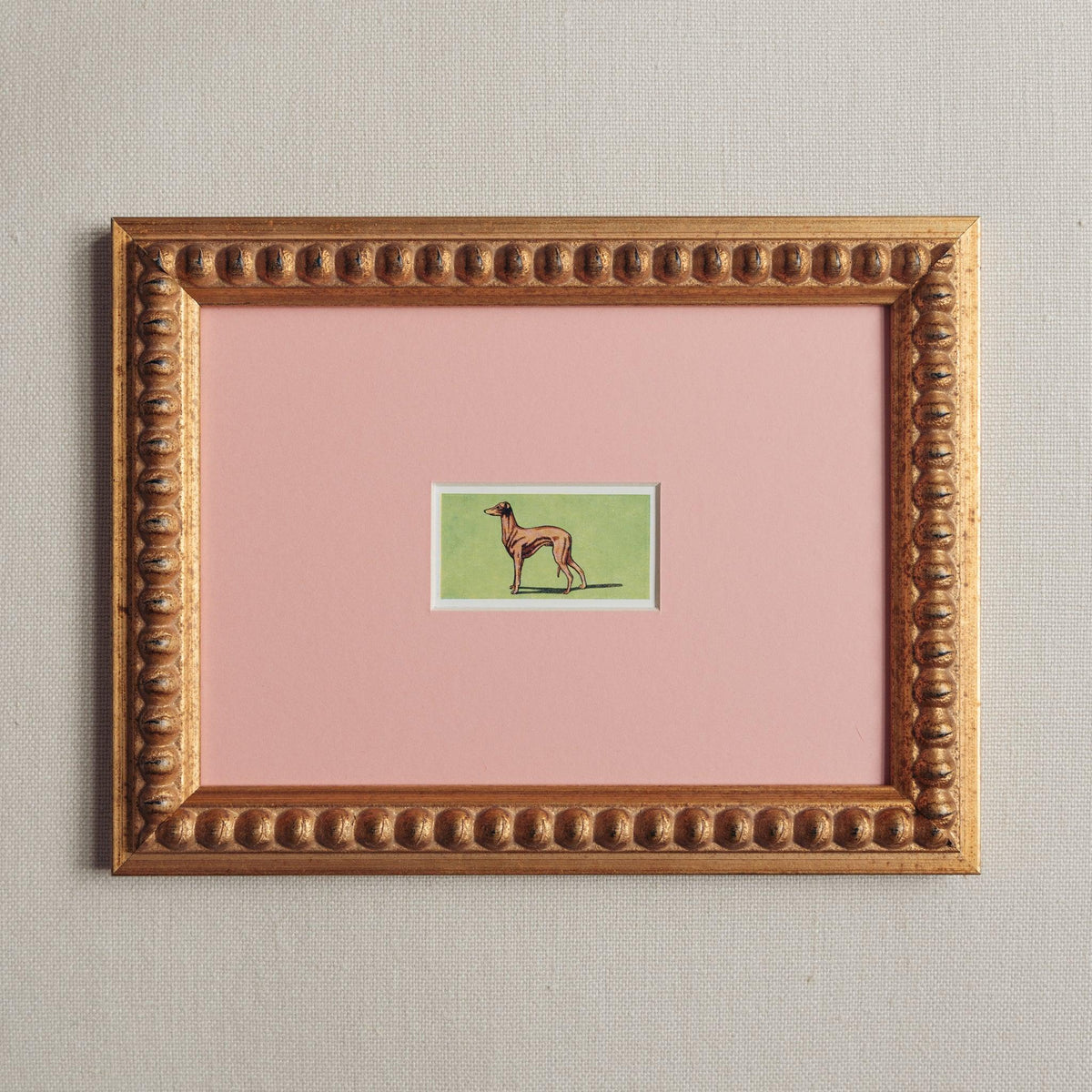 Handmade bobbin frame in antique gold style with pink mount, framing a tan whippet with a green background. Only available at Giddy Prints. 