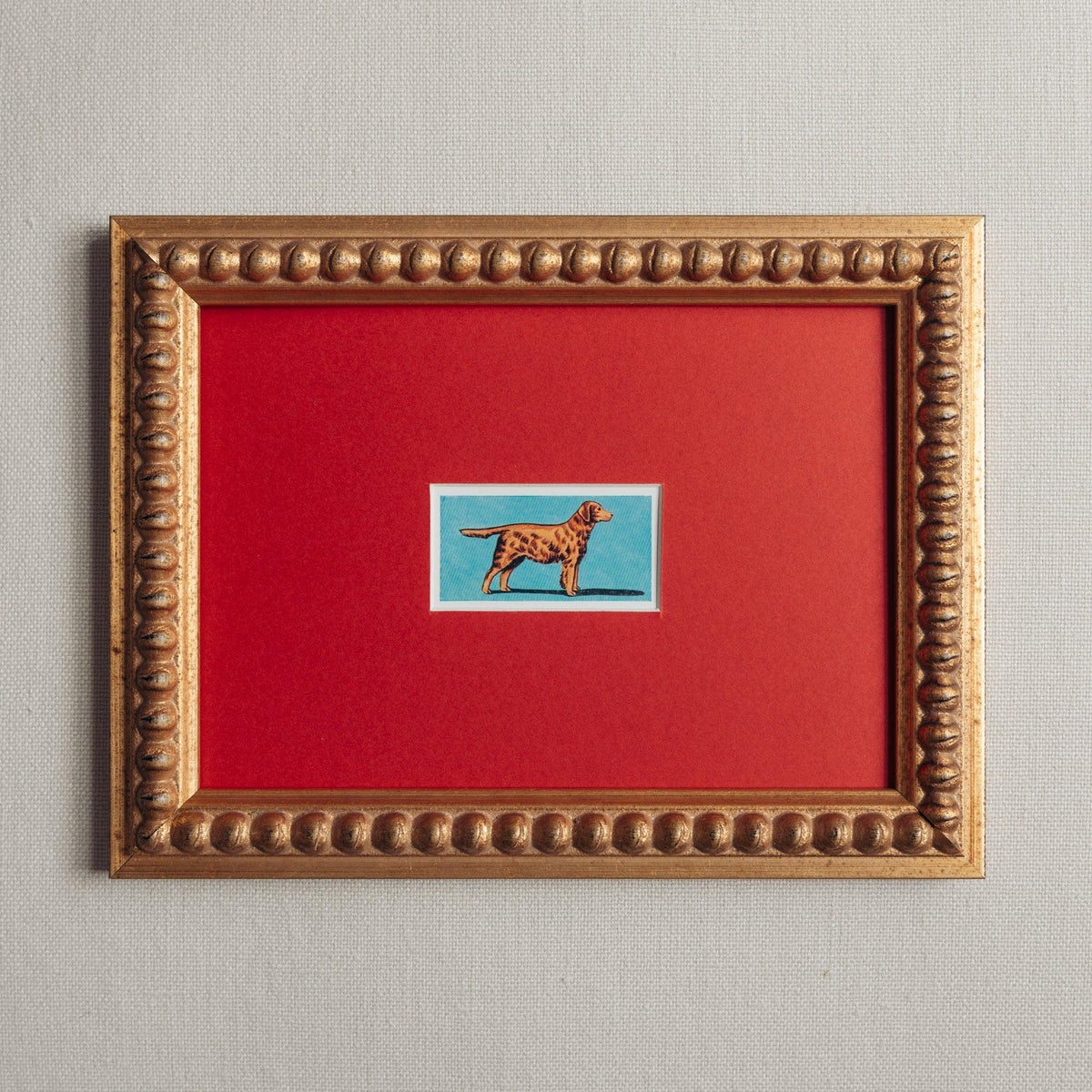 Handmade bobbin frame in antique style gold with red mount and a lithograph of a golden retriever on a blue background. 