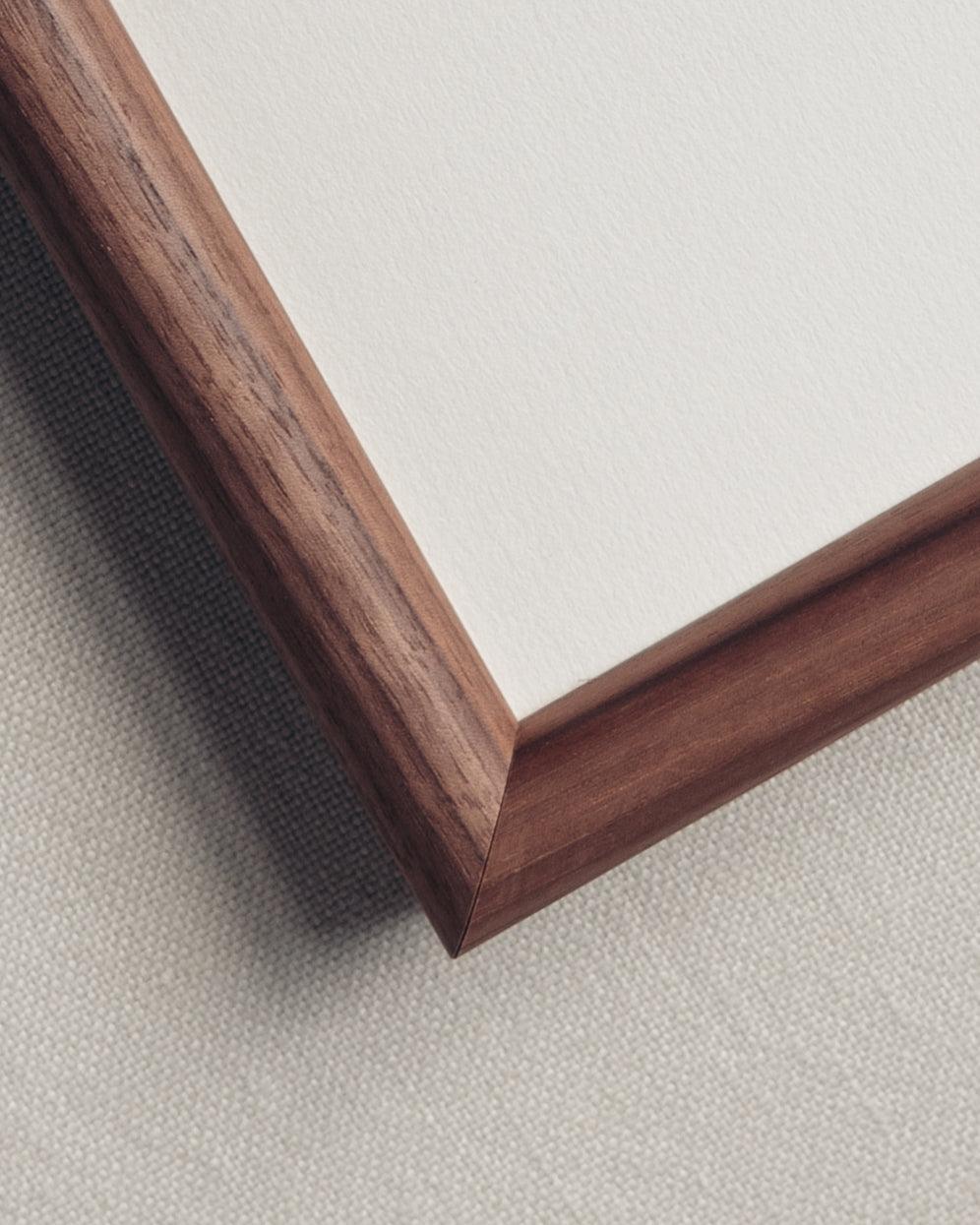 A detailed shot of the corner of the wooden frame in dark brown walnut veneer on a linen back drop. Available only at Giddy Prints. 